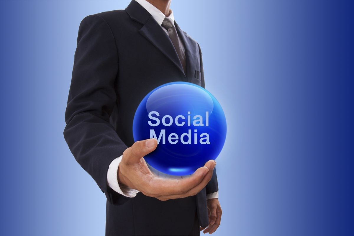 Businessman hand holding blue crystal ball with social media word